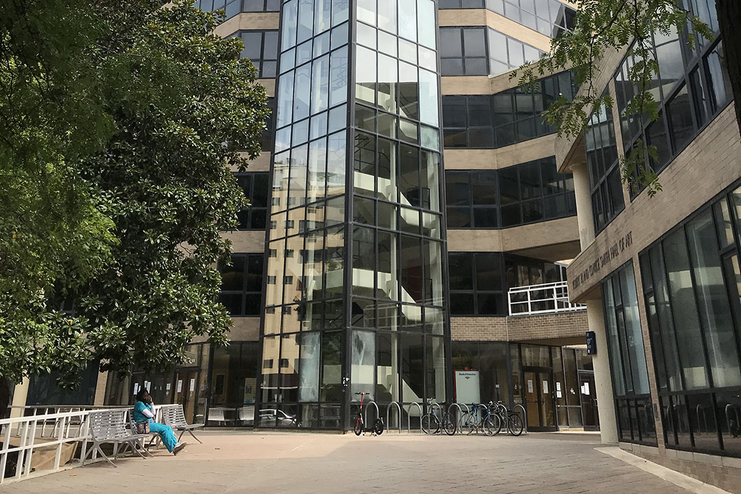 A person sitting on a bench outside the GW Academic Center, where the Language Center is located
