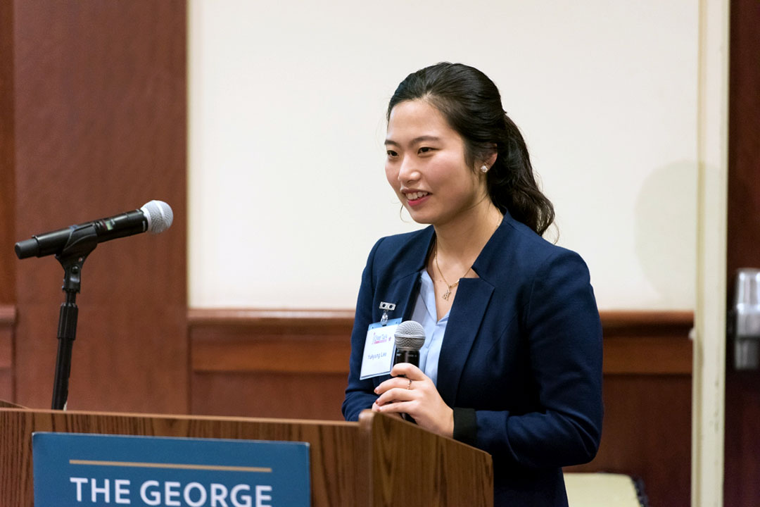 Student standing and talking into a microphone at a podium