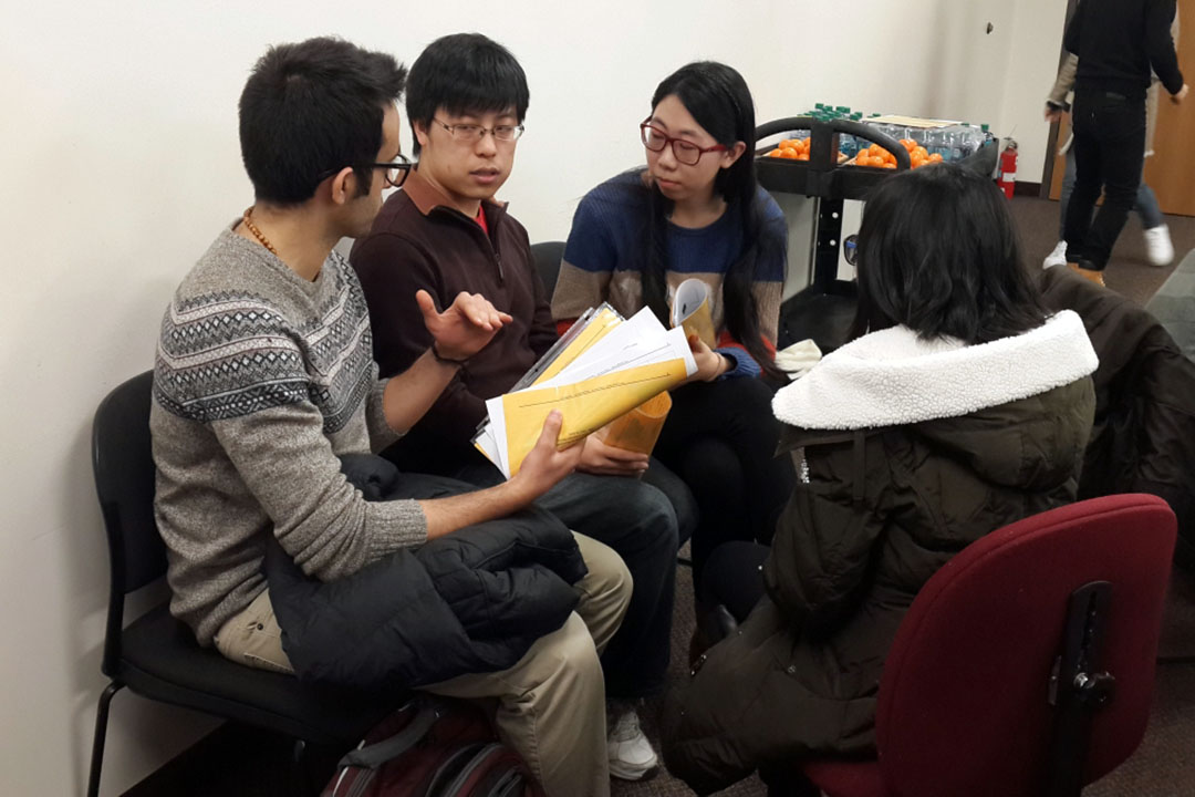 Four students sitting with papers and talking