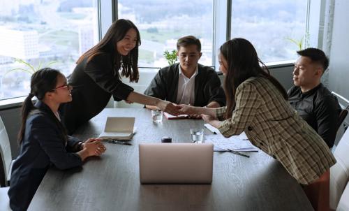 A group of business people at a conference table, with two people shaking hands